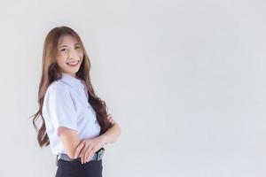 Portrait of an adult Thai student in university student uniform. Asian beautiful girl standing with her arms crossed confidently on white background. photo