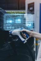 Hand plugging in a charger in an electric car socket.Electric car or ev is charging at station photo