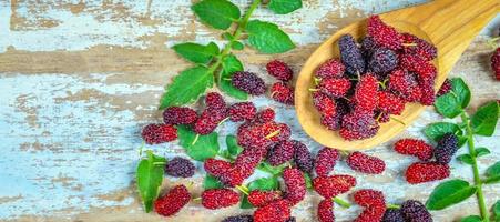 la morera orgánica fresca es una fuente saludable de vitaminas en el viejo fondo de madera. mezclar fruta de morera en tailandia. foto