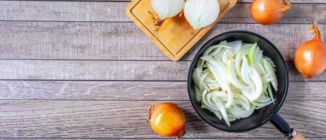 White onion slices in pan for cooking and fresh white onion on gray background.Top view photo