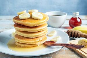 Stack of  banana pancakes with slices of fresh bananas, a Sweet Homemade Stack of Pancakes with Butter and Syrup for Breakfast in wooden background photo