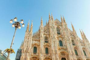 Famous church Milan Cathedral Duomo di Milano with Gothic spires and white marble statues. Top tourist attraction on piazza in Milan Lombardia Italy. Wide angle view of old Gothic architecture and art photo