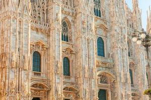 Famous church Milan Cathedral Duomo di Milano with Gothic spires and white marble statues. Top tourist attraction on piazza in Milan Lombardia Italy. Wide angle view of old Gothic architecture and art photo