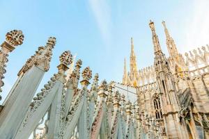 Roof of Milan Cathedral Duomo di Milano with Gothic spires and white marble statues. Top tourist attraction on piazza in Milan, Lombardia, Italy. Wide angle view of old Gothic architecture and art. photo