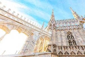 Roof of Milan Cathedral Duomo di Milano with Gothic spires and white marble statues. Top tourist attraction on piazza in Milan, Lombardia, Italy. Wide angle view of old Gothic architecture and art. photo