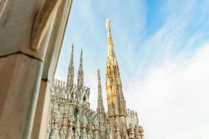 Roof of Milan Cathedral Duomo di Milano with Gothic spires and white marble statues. Top tourist attraction on piazza in Milan, Lombardia, Italy. Wide angle view of old Gothic architecture and art. photo