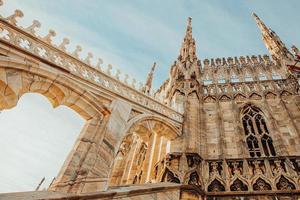 Roof of Milan Cathedral Duomo di Milano with Gothic spires and white marble statues. Top tourist attraction on piazza in Milan, Lombardia, Italy. Wide angle view of old Gothic architecture and art. photo