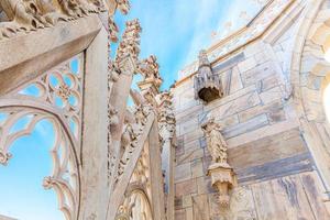 Roof of Milan Cathedral Duomo di Milano with Gothic spires and white marble statues. Top tourist attraction on piazza in Milan, Lombardia, Italy. Wide angle view of old Gothic architecture and art. photo