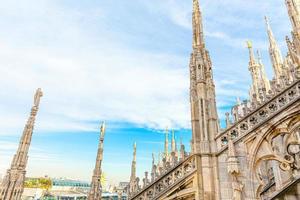 Roof of Milan Cathedral Duomo di Milano with Gothic spires and white marble statues. Top tourist attraction on piazza in Milan, Lombardia, Italy. Wide angle view of old Gothic architecture and art.