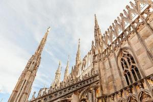 Roof of Milan Cathedral Duomo di Milano with Gothic spires and white marble statues. Top tourist attraction on piazza in Milan, Lombardia, Italy. Wide angle view of old Gothic architecture and art. photo