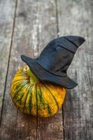 Jack O Lantern Halloween pumpkin with black witch hat on wooden background. Halloween party concept. Holiday season greeting, trick of treat spooky. photo