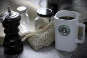 WASHINGTON - USA September, 26 2022  Starbucks coffee mug on gray table with coffee bottle and coffee grinder. photo