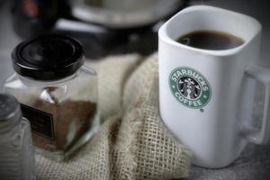 WASHINGTON - USA September, 26 2022  Starbucks coffee mug on gray table with coffee bottle and coffee grinder. photo
