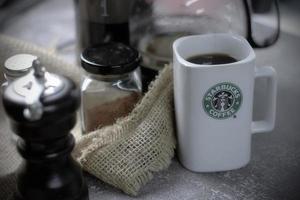 WASHINGTON - USA September, 26 2022  Starbucks coffee mug on gray table with coffee bottle and coffee grinder. photo