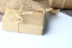 Holidays Gifts Christmas and New Year Gift box wrapped in brown paper, pine cones and white paper and pens placed on the table copy space. photo