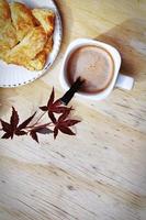 Coffee mugs and pastries served on a wooden table with crimson Japanese maple leaves and white daisies. Top view photo. photo