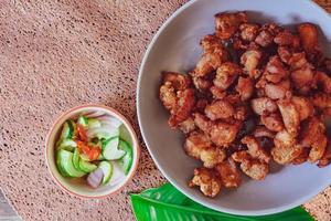 Fried Pork Belly with Fish Sauce and Sticky Rice Served on a white plate on a black wooden floor. photo