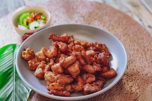 Fried Pork Belly with Fish Sauce and Sticky Rice Served on a white plate on a black wooden floor. photo