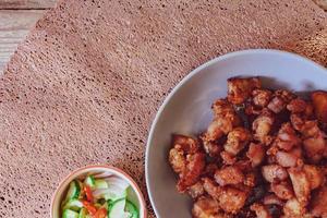 Fried Pork Belly with Fish Sauce and Sticky Rice Served on a white plate on a black wooden floor. photo