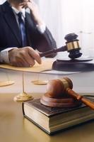 Justice and law concept.Male judge in a courtroom with the gavel, working with, computer and docking keyboard, eyeglasses, on table in morning light photo