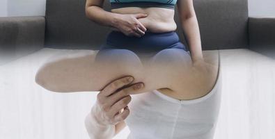 hermosa mujer gorda con cinta métrica usa su mano para exprimir el exceso de grasa que está aislado en un fondo blanco. ella quiere perder peso, el concepto de cirugía y descomponer grasa bajo el foto