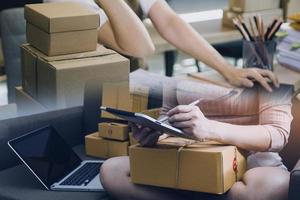 Startup SME small business entrepreneur of freelance Asian woman using a laptop with box Cheerful success Asian woman her hand lifts up online marketing packaging box and delivery SME idea concept photo