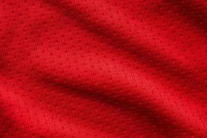 Red fabric sport clothing football jersey with air mesh texture background photo