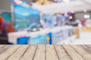 Wood table over Television shelf in eletronic store blurred background photo