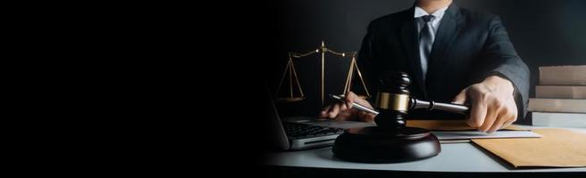 Justice and law concept.Male judge in a courtroom with the gavel, working with, computer and docking keyboard, eyeglasses, on table in morning light photo