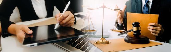 Business and lawyers discussing contract papers with brass scale on desk in office. Law, legal services, advice, justice and law concept picture with film grain effect photo