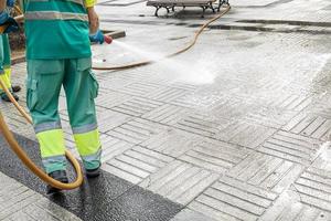 Worker cleaning a city square with water using a hosepipe. Public maintenance concept. Copy space photo