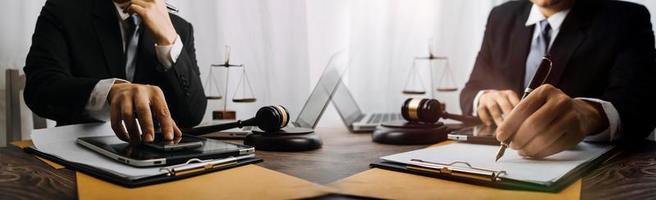 Business and lawyers discussing contract papers with brass scale on desk in office. Law, legal services, advice, justice and law concept picture with film grain effect photo