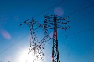 silhouette electric towers supporting copper cables to transport electric energy photo