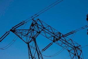 silhouette electric towers supporting copper cables to transport electric energy photo