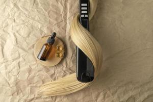 A hair treatment essential oil for smoothing hair lying on a strand of blond hair photo