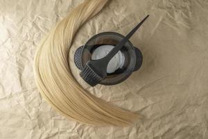 A strand of blonde hair lying next to the brush for coloring and hair dye photo