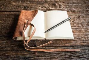 The opened diary leather book with blank space on the wood table. The education and learning concept. photo