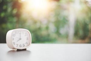 A white clock is placed on a wooden table, the concept of extinction of time, countdown, new beginning, appreciation of life, valuable use of time. photo