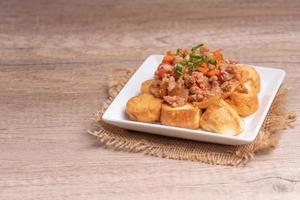 Fried tofu stir fried with ground pork and vegetables in white plate photo