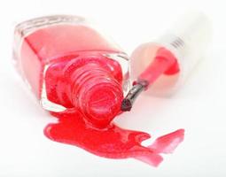 bottle with spilled red nail polish on white photo