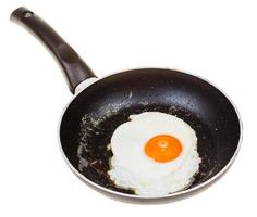 one fried egg in black frypan isolated on white photo