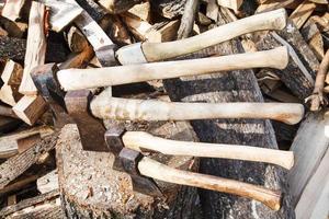 axes in wood block near stack of firewoods photo