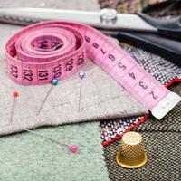 cinta métrica rosa, alfileres, dedal, tijeras en tejido foto