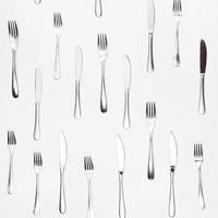 table knives and forks arranged on white photo