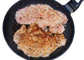 top view of two schnitzels are fried in pan photo