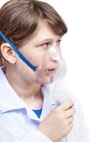 girl breathes with face mask of modern nebulizer photo