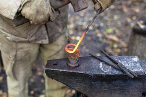 Blacksmith cut out a buckle with hammer and chisel photo