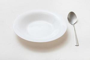 white deep plate and spoon on plaster photo