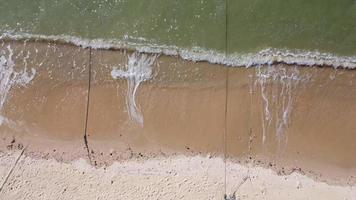 schöne meereswellen und weißer sandstrand auf der tropischen insel. sanfte wellen des blauen ozeans auf sandstrandhintergrund von der draufsicht von drohnen. video