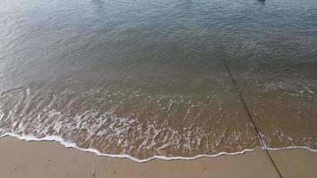 bellissimo mare onde e bianca sabbia spiaggia nel il tropicale isola. morbido onde di blu oceano su sabbioso spiaggia sfondo a partire dal superiore Visualizza a partire dal droni. video